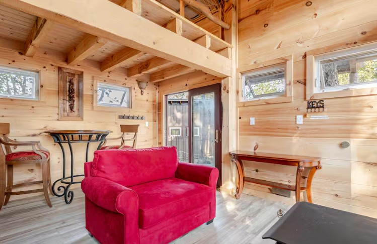 Living room with red sofa and wooden decor at treehave treehouse in North Carolina.