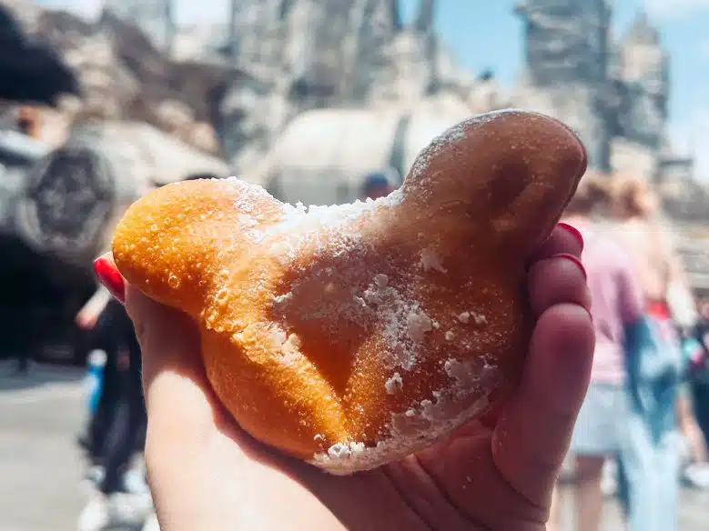Victoria holding a Mickey-shaped beignet