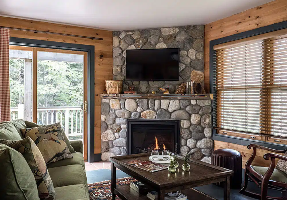 Living area with a fireplace in a woodland cabin at the Claremont Hotel.