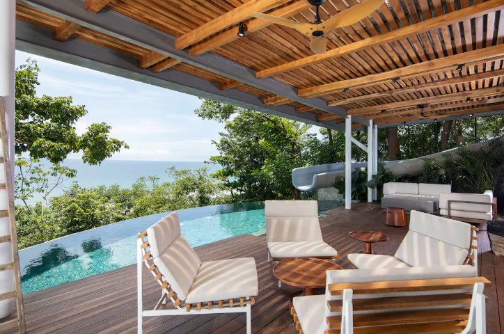 Shaded patio overlooking the infinity pool with two seating areas and a firetable at a villa in Malpais.